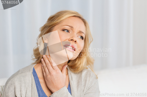 Image of unhappy woman suffering from throat pain at home