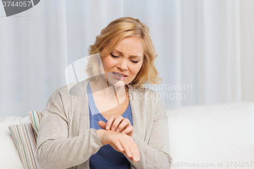 Image of unhappy woman suffering from hand inch at home