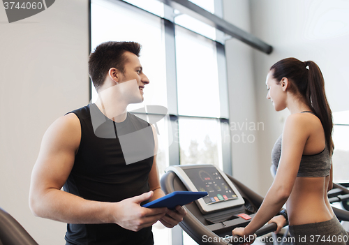 Image of happy woman with trainer on treadmill in gym