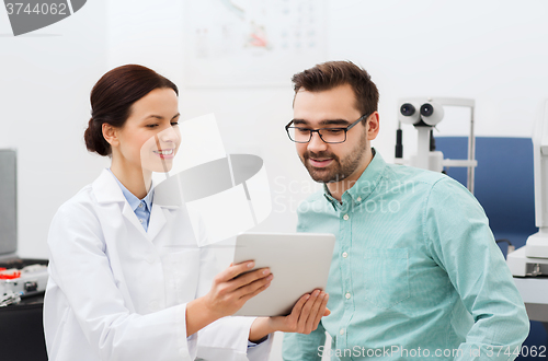 Image of optician with tablet pc and patient at eye clinic