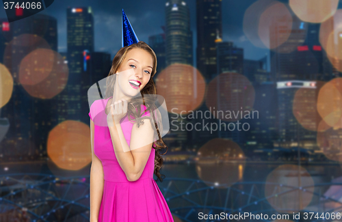 Image of happy young woman in party cap over night city 