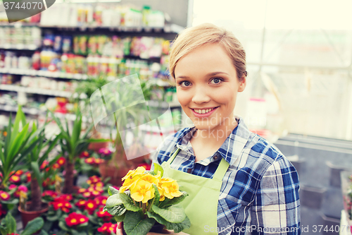 Image of happy woman holding flowers in greenhouse