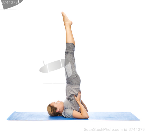 Image of woman making yoga in shoulderstand pose on mat