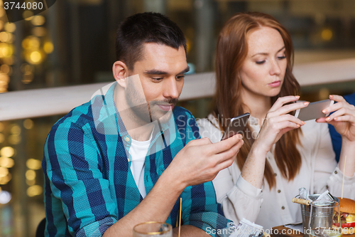 Image of couple with smartphones dining at restaurant