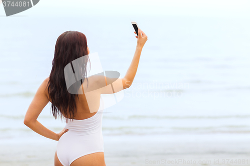 Image of young woman taking selfie with smartphone