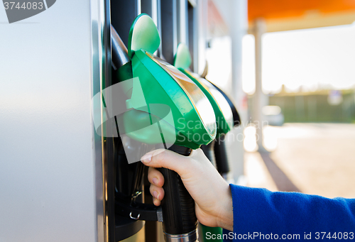 Image of close up of hand holding hose at gas station