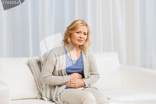 Image of unhappy woman suffering from stomach ache at home