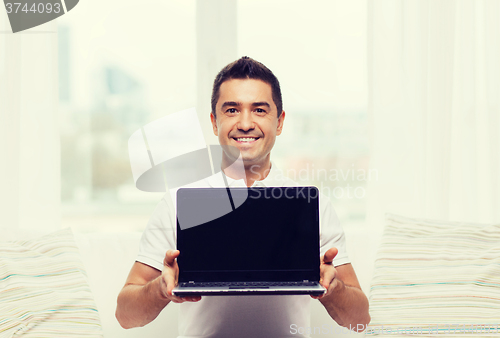 Image of happy man showing laptop blank screen at home
