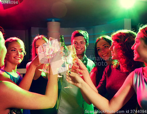 Image of smiling friends with wine glasses and beer in club