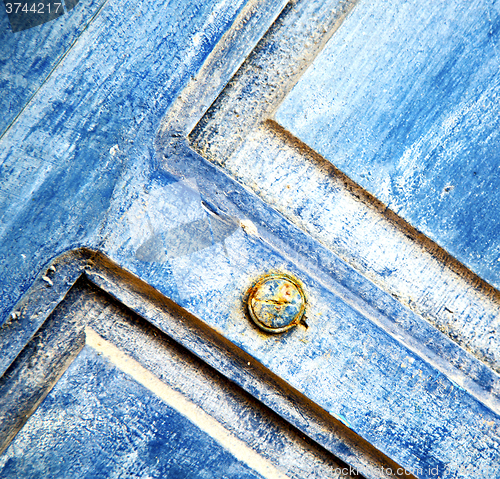 Image of stripped paint in the blue wood door and rusty nail