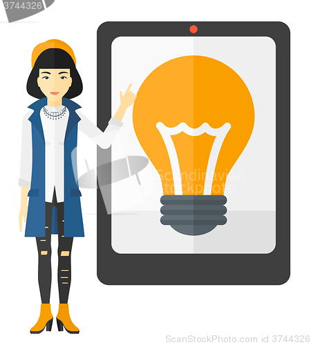 Image of Woman pointing at tablet computer with light bulb on screen.
