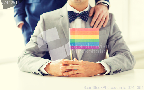 Image of close up of male gay couple holding rainbow flag