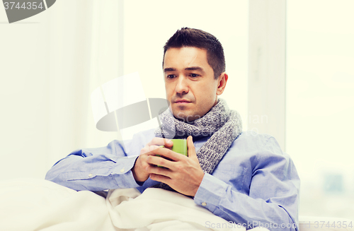 Image of ill man with flu drinking hot tea from cup at home