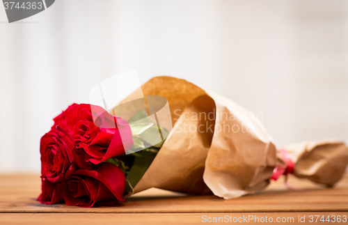 Image of close up of red roses bunch wrapped into paper