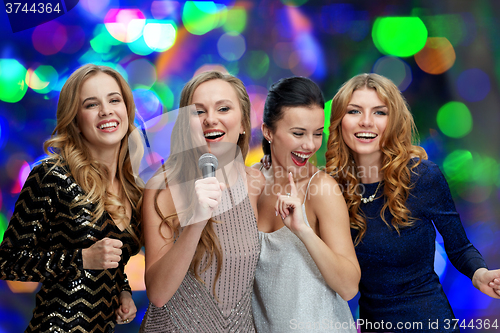 Image of happy young women with microphone singing karaoke