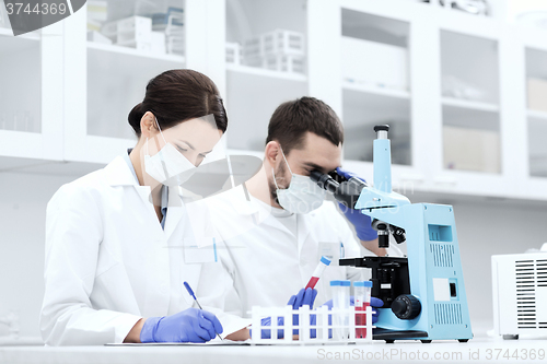 Image of scientists with clipboard and microscope in lab