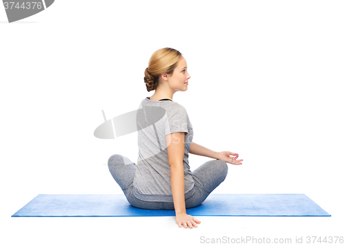 Image of woman making yoga in twist pose on mat
