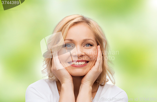 Image of smiling woman in white t-shirt touching her face