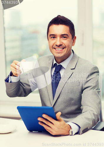 Image of smiling businessman with tablet pc and coffee cup