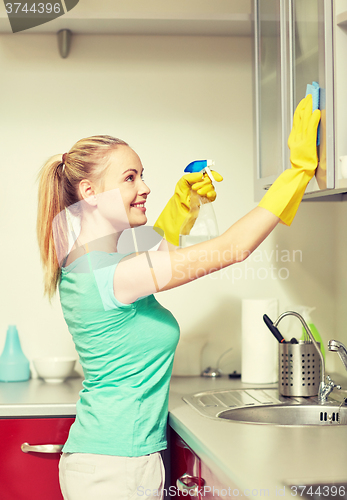 Image of happy woman cleaning cabinet at home kitchen