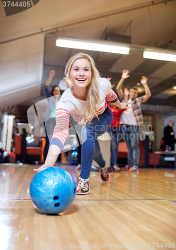 Image of happy young woman throwing ball in bowling club