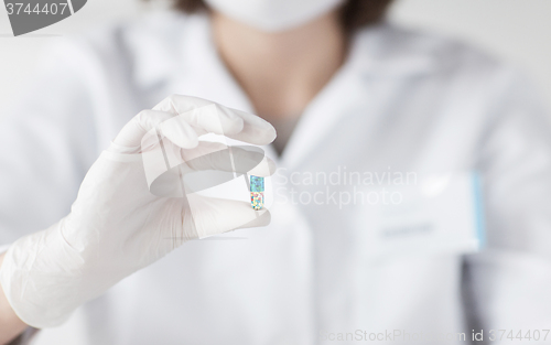 Image of close up of scientist holding pill in lab