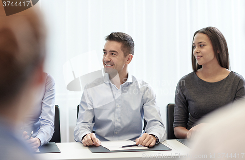 Image of group of smiling businesspeople meeting in office