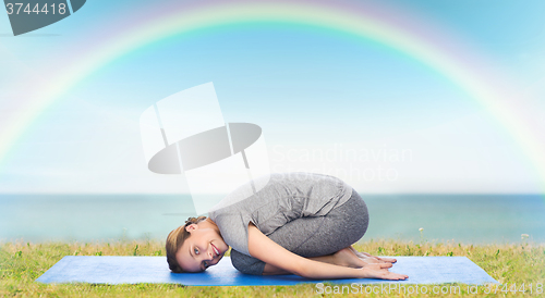 Image of happy woman making yoga in child pose on mat