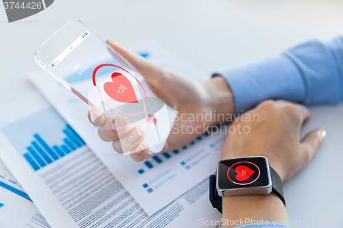 Image of hands with heart icon on smartphone and smartwatch