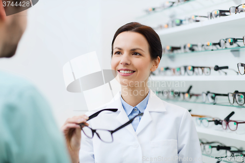 Image of optician showing glasses to man at optics store