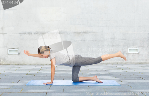 Image of woman making yoga in balancing table pose on mat