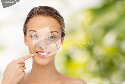 Image of happy young woman pointing finger to her smile