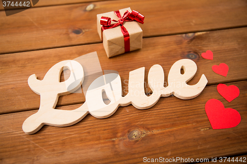 Image of close up of word love with gift box and red hearts