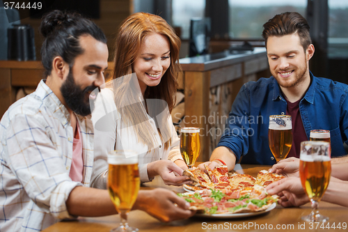 Image of friends eating pizza with beer at restaurant