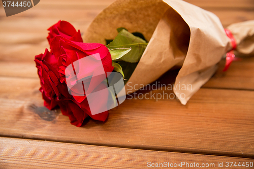 Image of close up of red roses bunch wrapped into paper