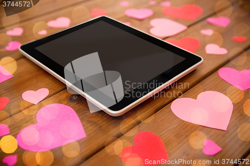 Image of close up of tablet pc and hearts on wood