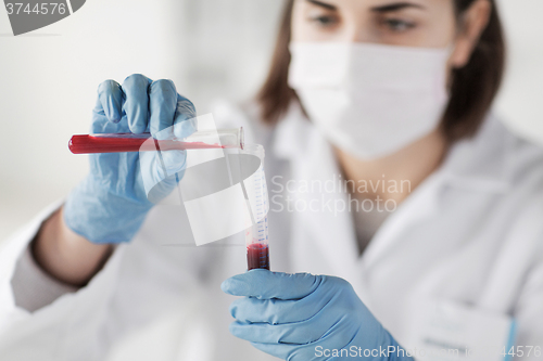 Image of close up of scientist with tube making test in lab