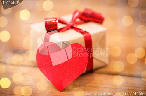 Image of close up of gift box and heart shaped note on wood