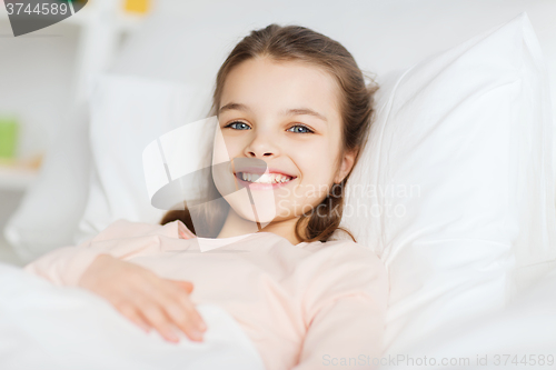 Image of happy smiling girl lying awake in bed at home