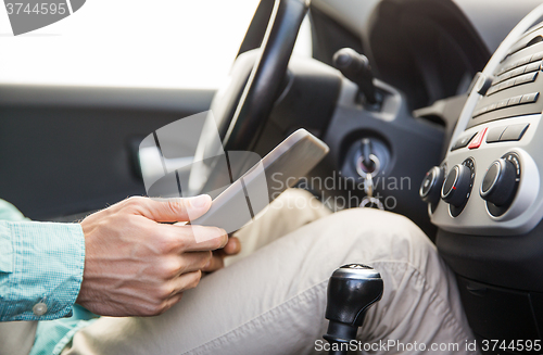 Image of close up of young man with tablet pc driving car