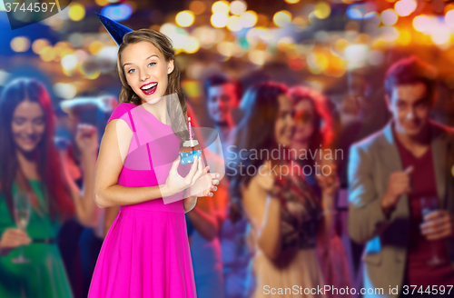 Image of happy woman with birthday cupcake at night club