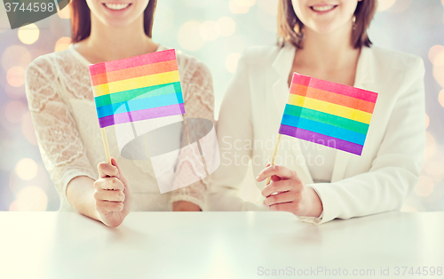 Image of close up of happy lesbian couple with rainbow flag