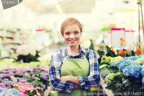 Image of happy woman with flowers in greenhouse