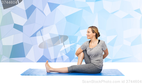 Image of woman making yoga in twist pose on mat