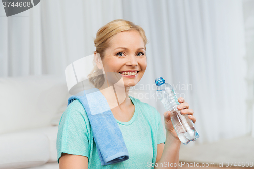 Image of happy woman drinking water and exercising at home