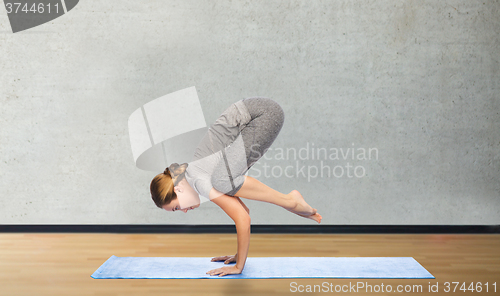 Image of woman making yoga in crane pose on mat