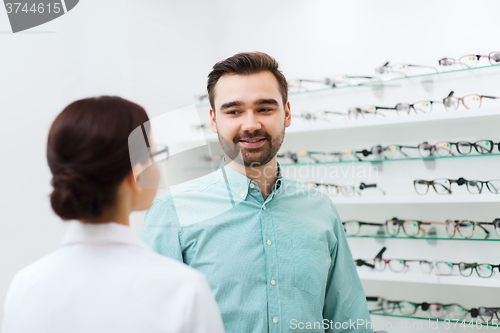 Image of optician showing glasses to man at optics store