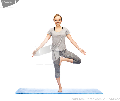 Image of woman making yoga in tree pose on mat