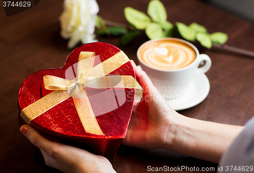Image of close up of hands holding heart shaped gift box