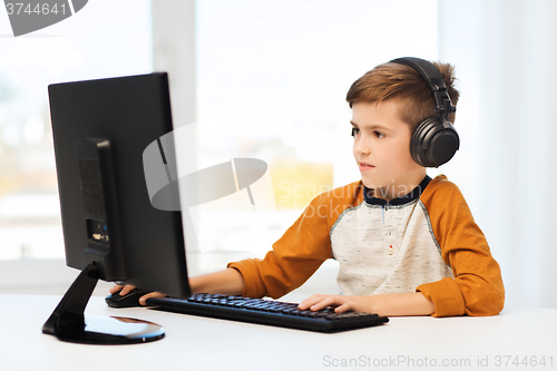 Image of happy boy with computer and headphones at home